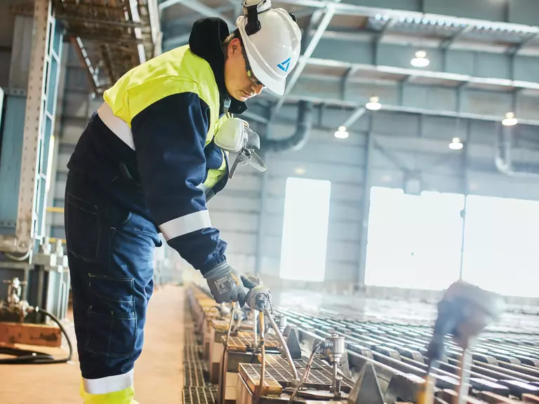 Aurubis plant workers wearing protective clothing, goggles and helmets at work