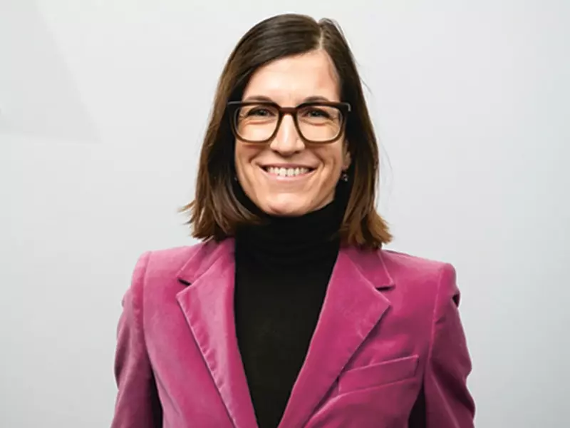  Laura Zielinski, Senior Vice President HR Group, wearing glasses, with shoulder-length brown hair, a black turtleneck jumper and a pink blazer.