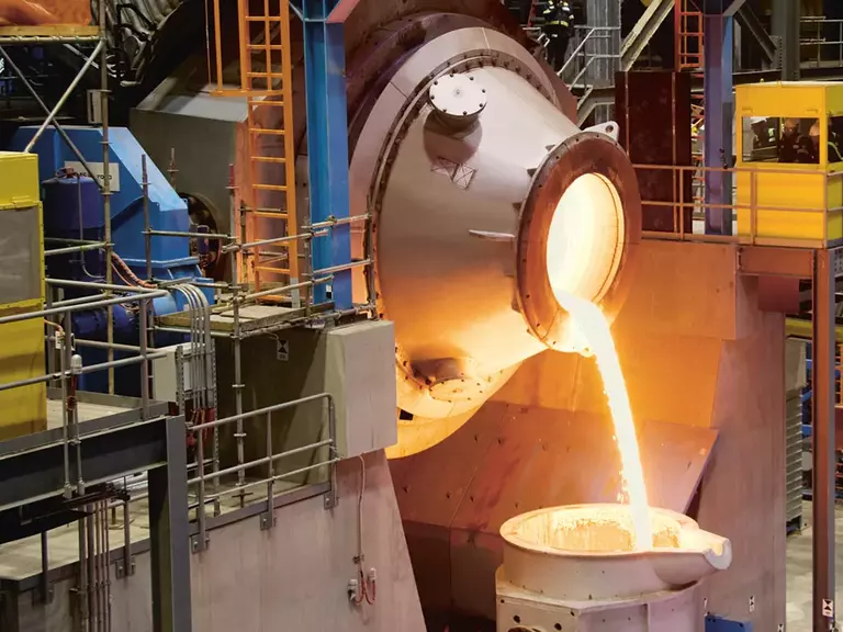Hot, liquid metal being poured into a cauldron.