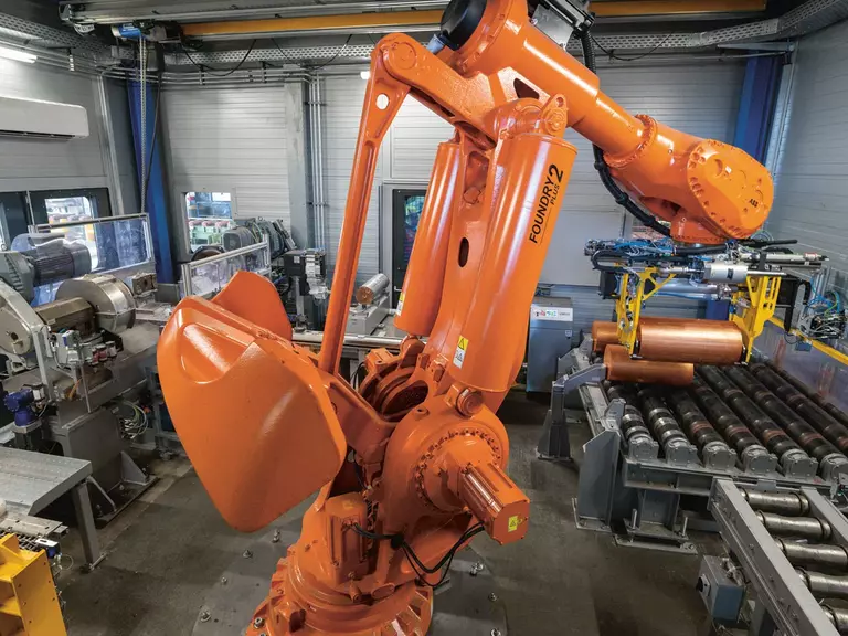 Orange robotic arm of a continuous casting machine at work